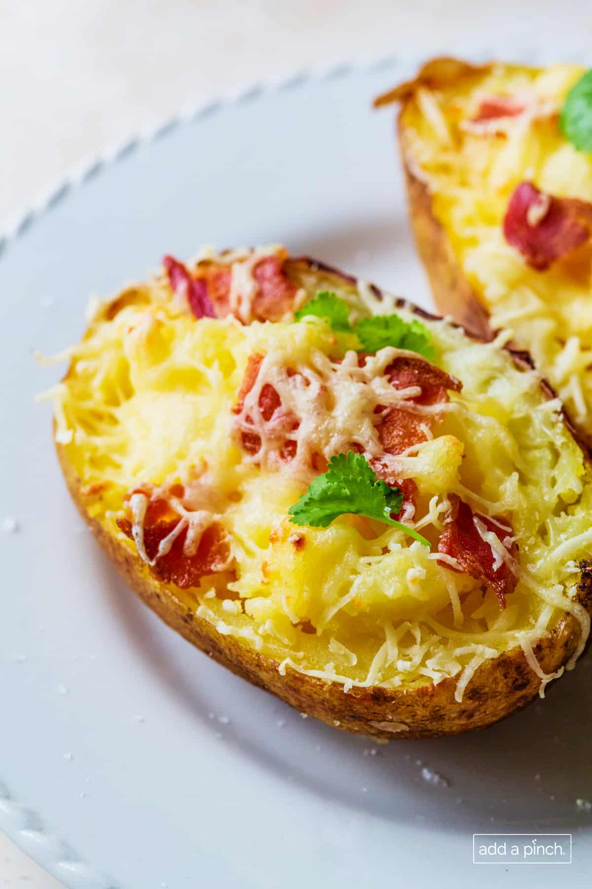 Twice baked potatoes topped with cheese and bacon served on a white plate.