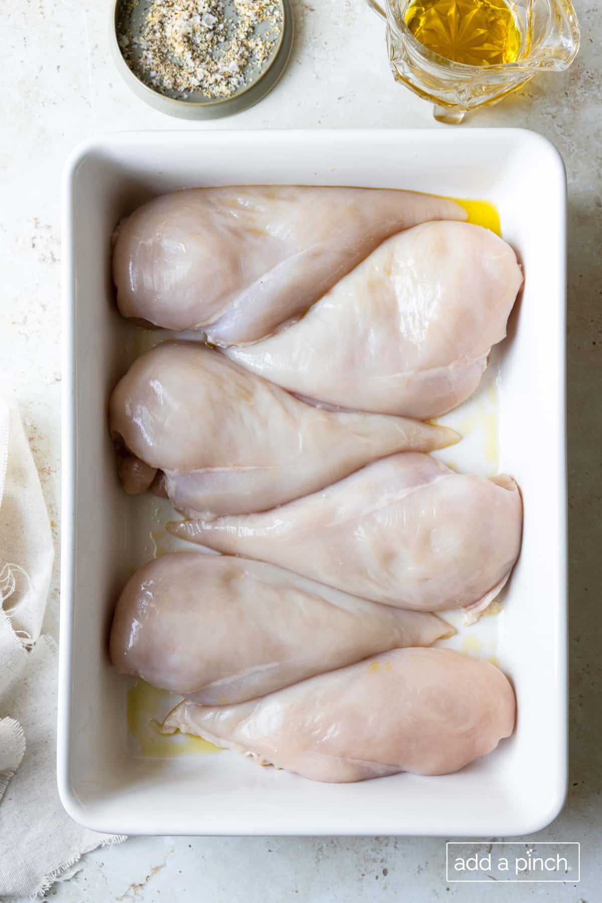 Ingredients used to make the best baked chicken recipe - fresh boneless skinless chicken breasts, olive oil, and Stone House Seasoning.