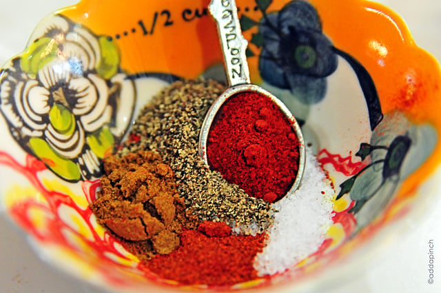 Colorful measuring bowl with dry spices and pewter measuring spoon.