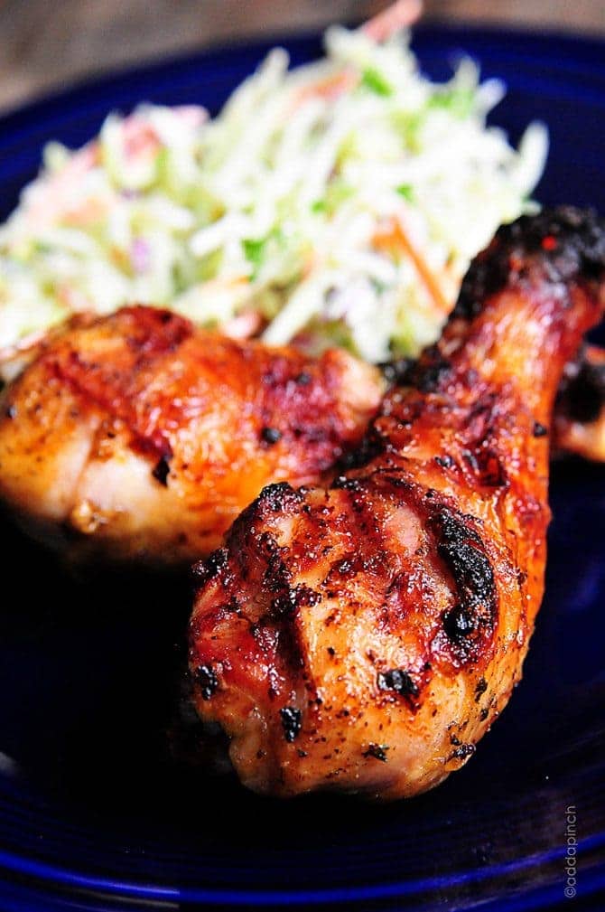 Chicken legs with grill marks, and coleslaw on a blue plate.