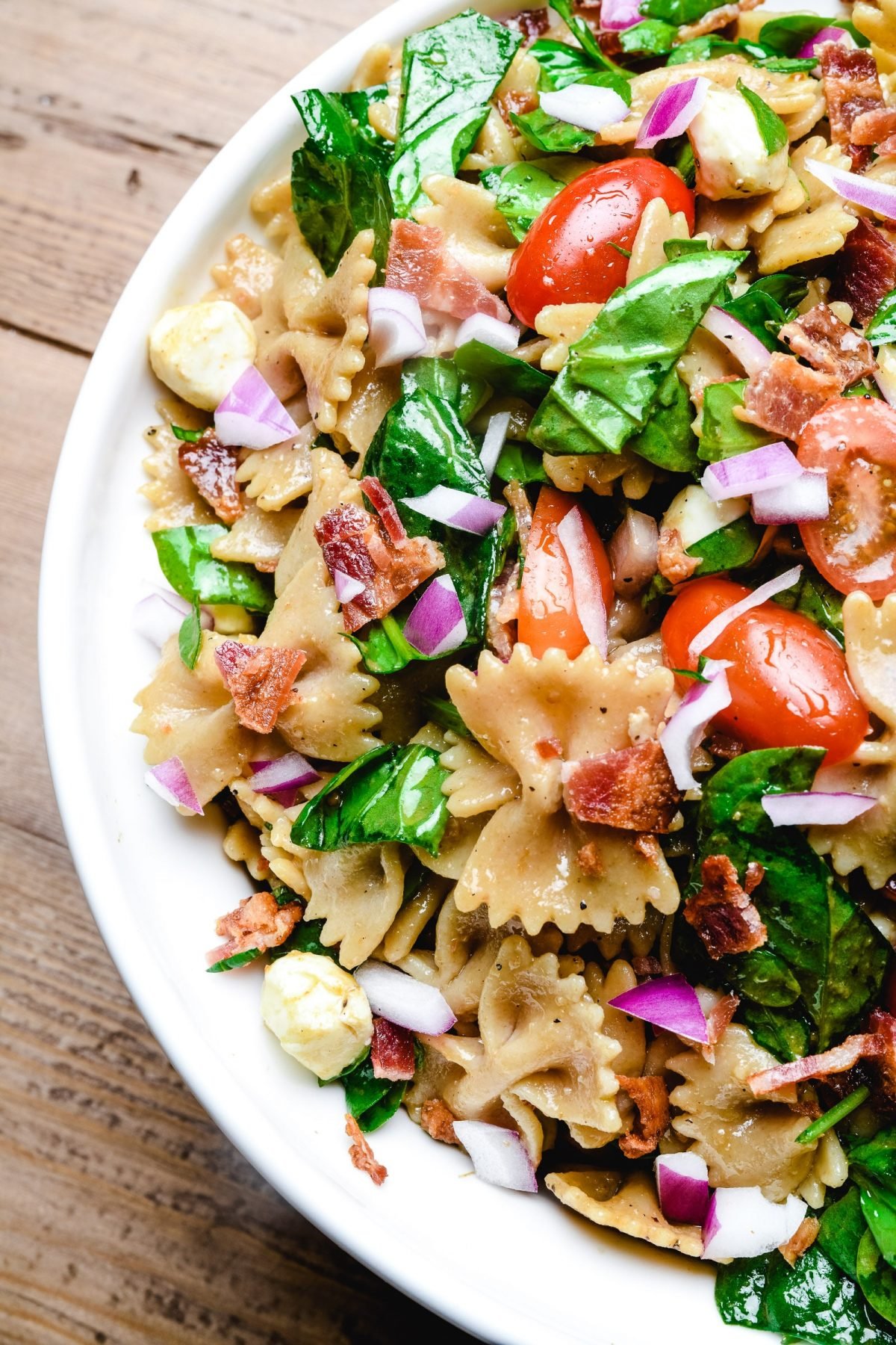 Mixed pasta salad with bacon, spinach and tomatoes.