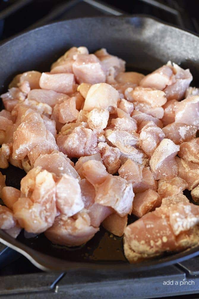 Chicken pieces have been coated in corn starch and placed in skillet to brown.
