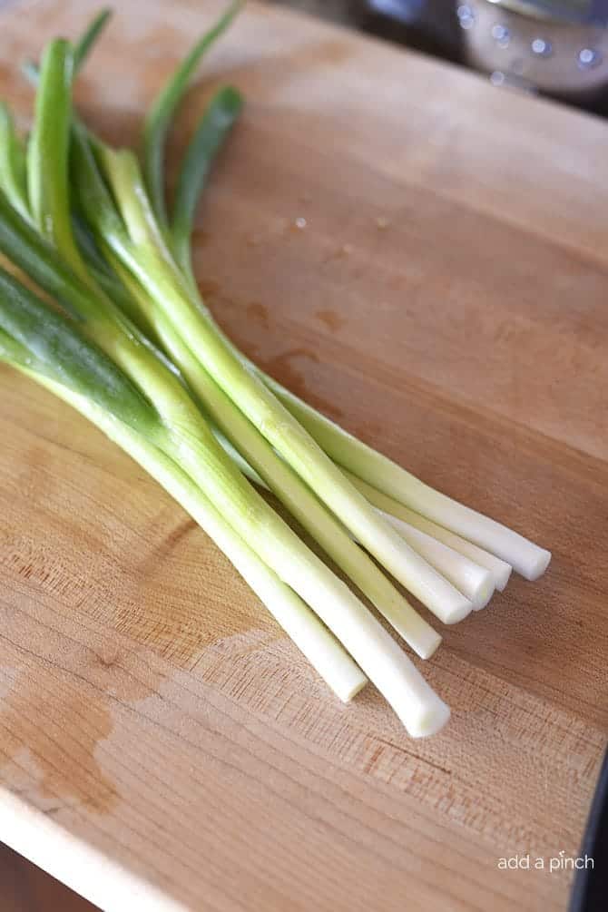 Green onions on a cutting board ready to chop.