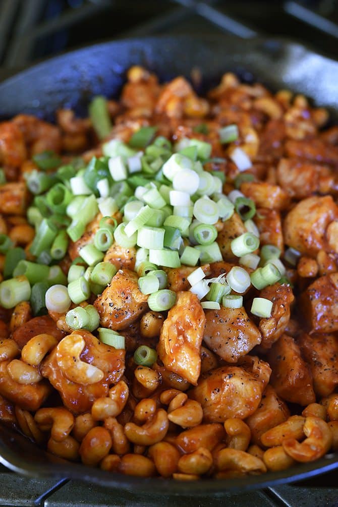 Cashew chicken has been topped with fresh chopped green onions.