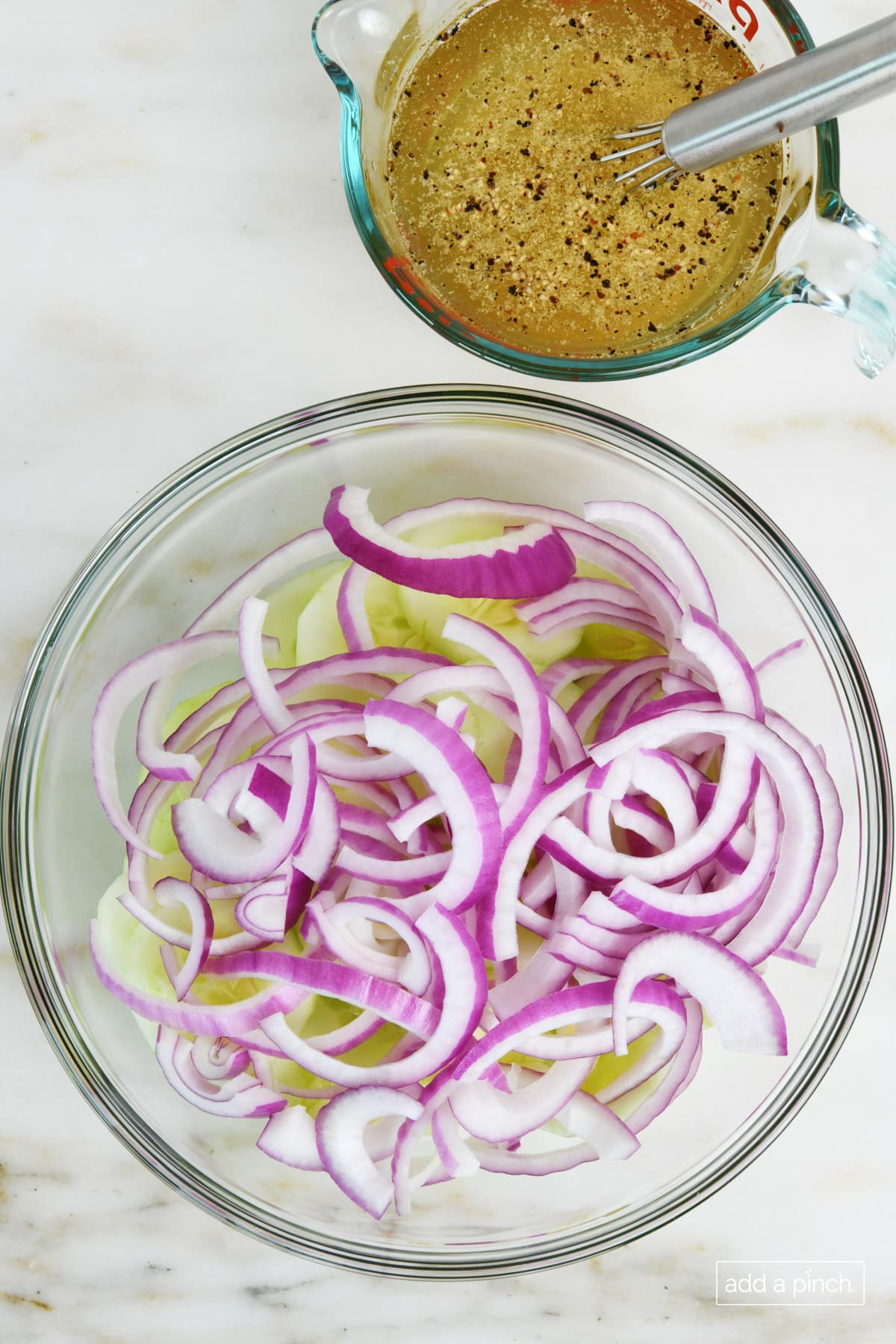 Bowl of cucumbers and onions with vinegar dressing at the side.