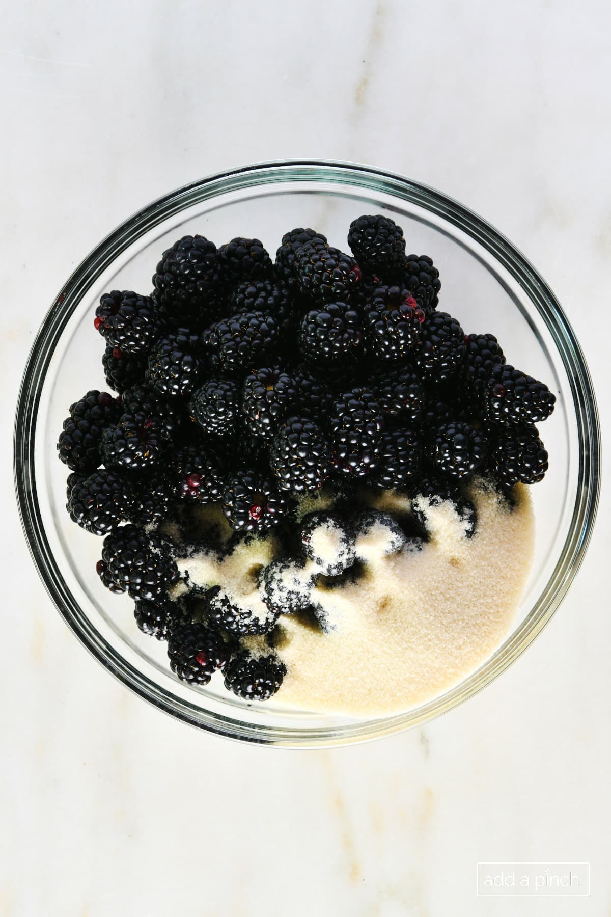 Blackberries and sugar in a glass bowl.