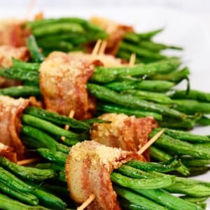 White platter filled with green bean bundles wrapped in bacon.