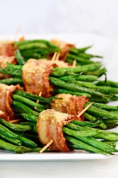White platter filled with green bean bundles wrapped in bacon.