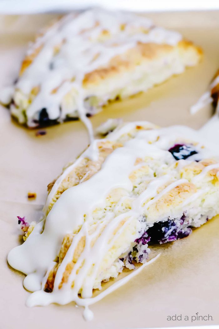 Lemon blueberry scones are on a parchment sheet.