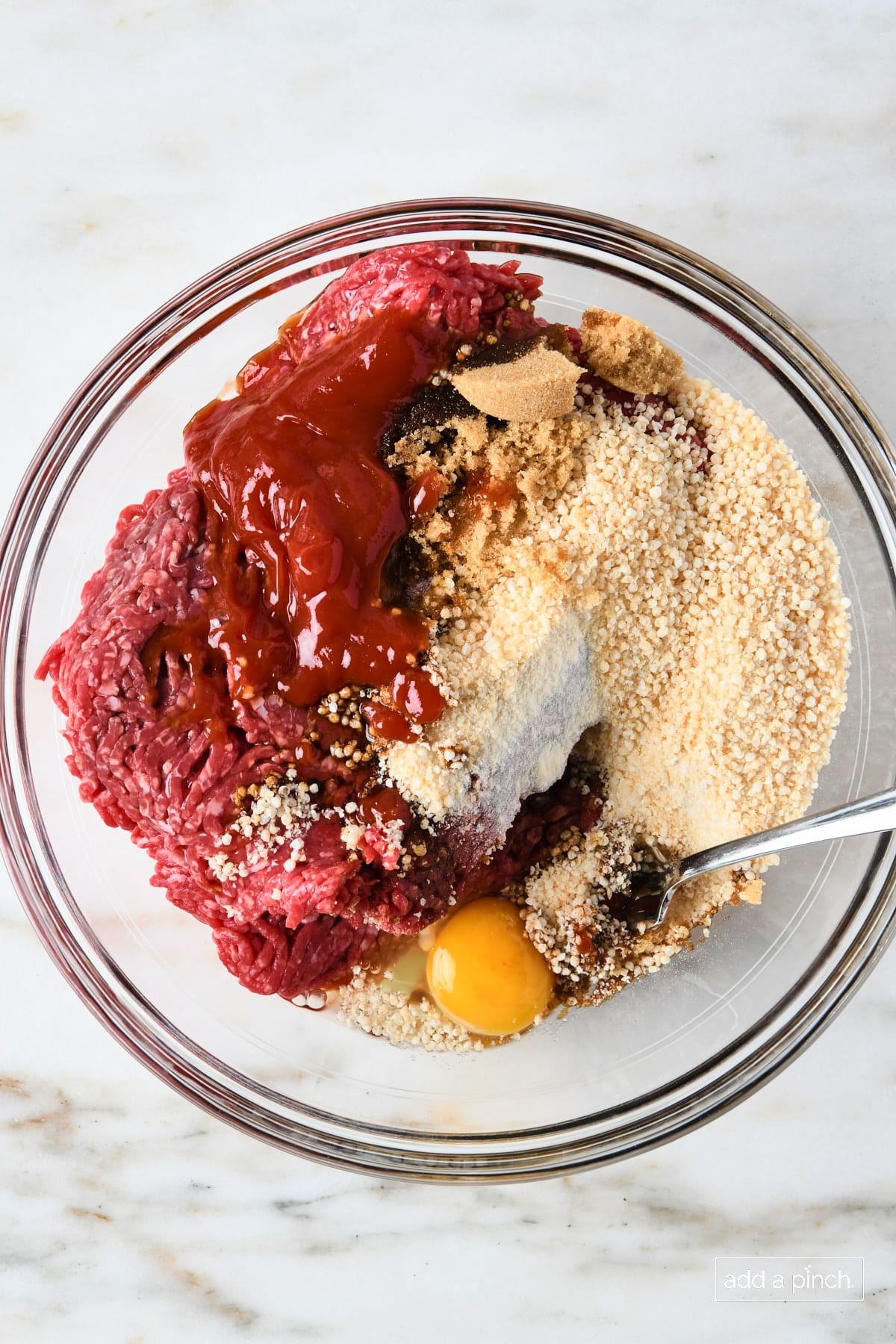 Ingredients to make meatloaf muffins in a glass bowl with a fork.