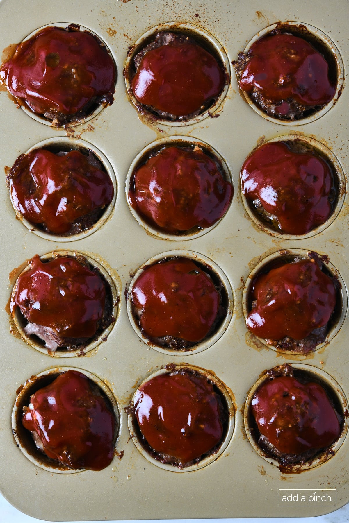 Baked mini meatloaf muffins in a muffin pan.