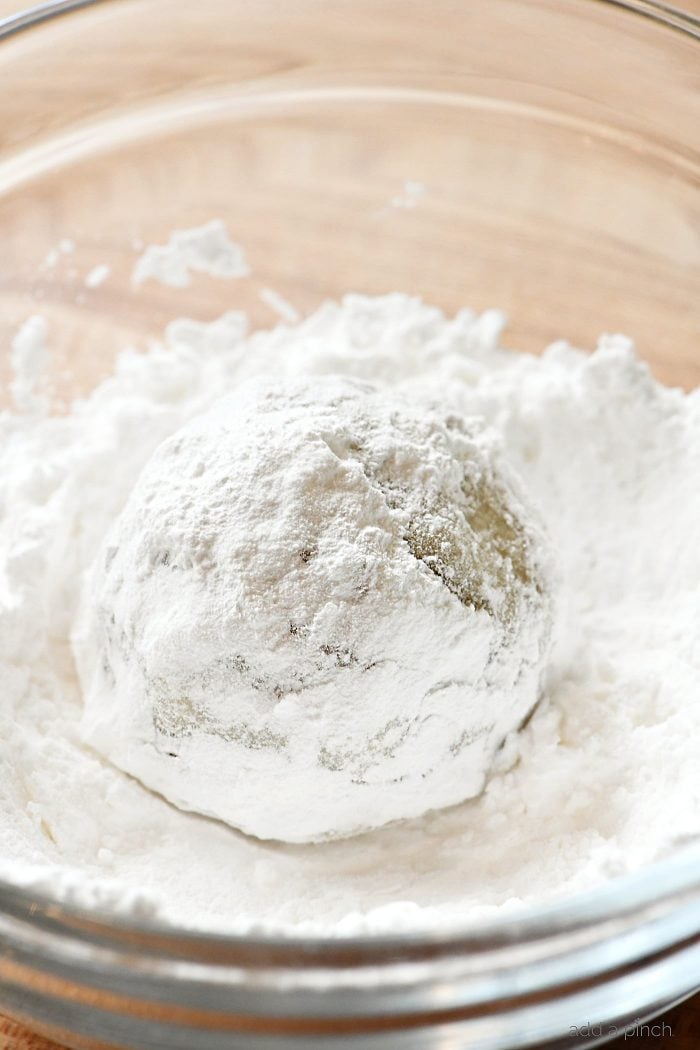 Snowball Cookie being rolled in bowl of powdered sugar