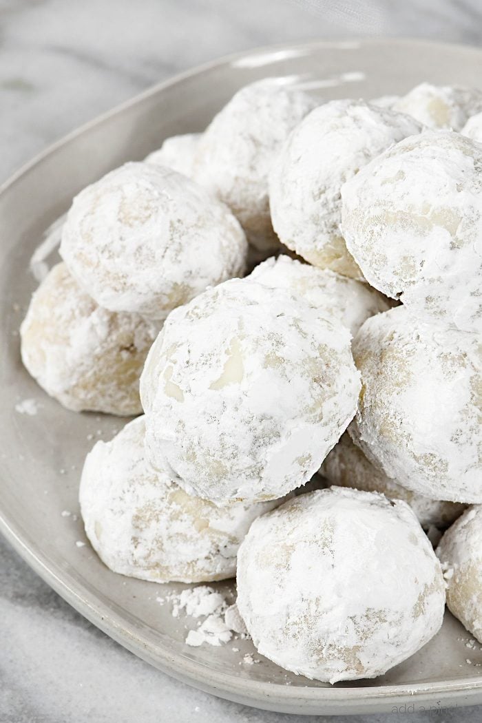 Pecan Sandies or Snowball Cookies, also called Mexican Wedding Cookies, covered in powdered sugar, stacked on plate