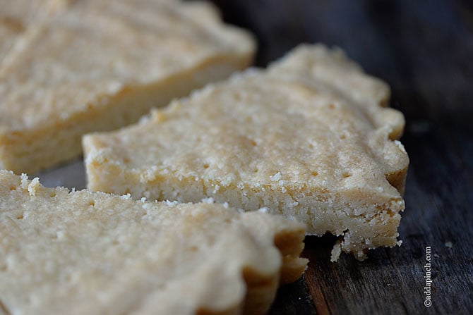 Triangle slices of thick shortbread sits on a wooden tray.