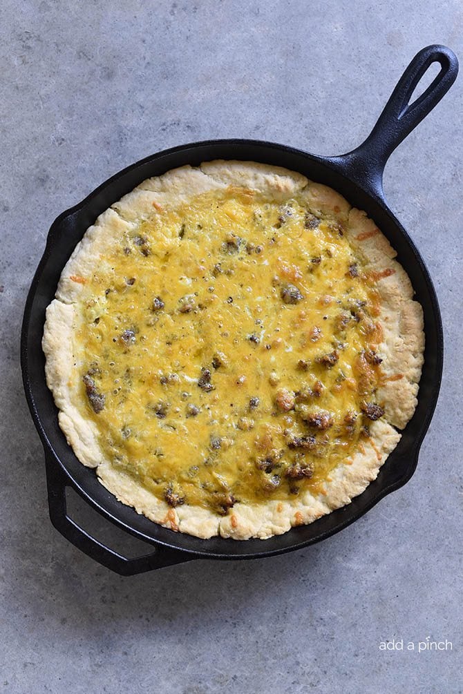 Iron skillet with sausage cheese quiche with browned biscuit crust.