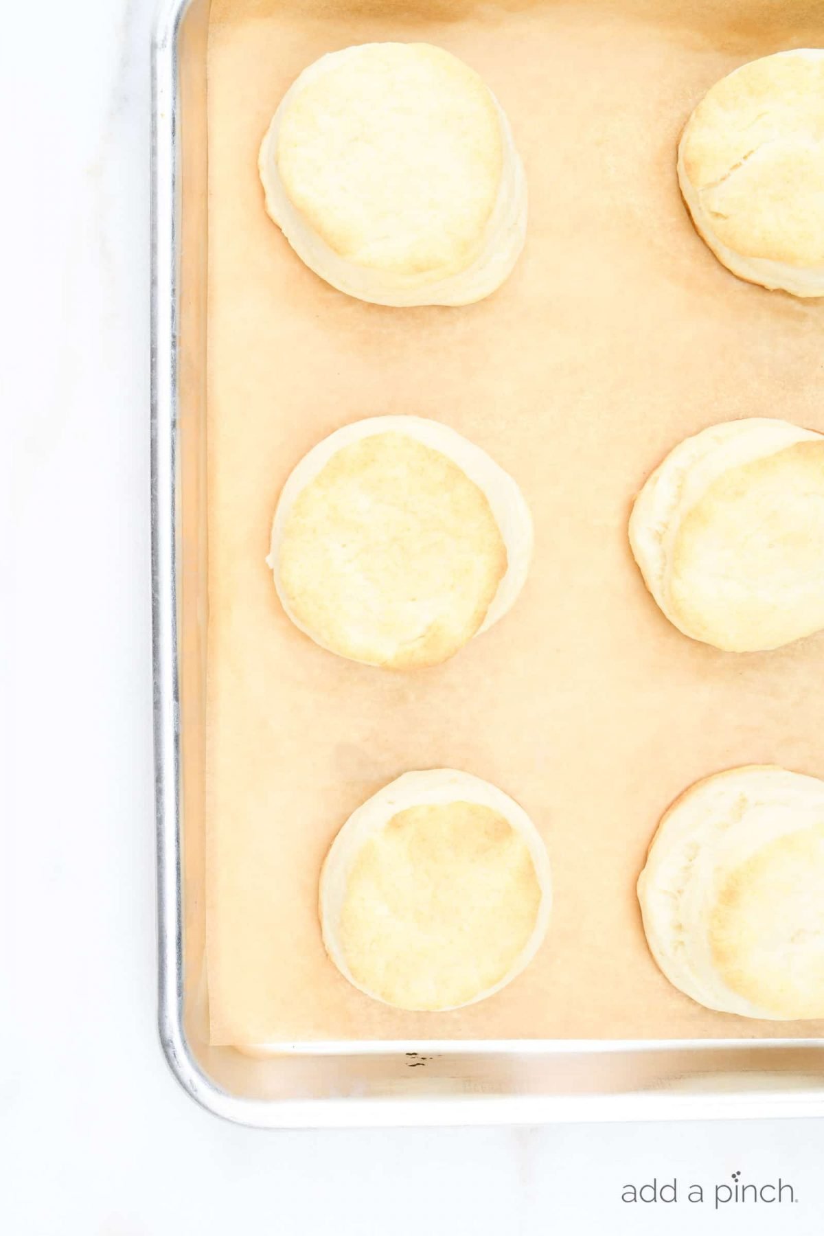 Photograph of biscuits on a baking sheet on a white background.