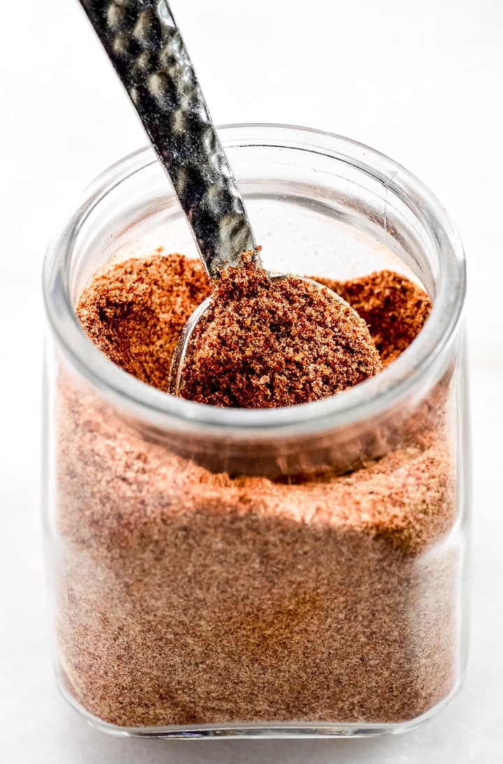 Glass jar and silver spoon with hammered handle along with homemade taco seasoning.